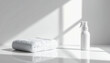 © PHAISITSAWAN - White towel and clear spray bottle on bright white surface for disinfecting and cleaning in modern home environment