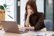 © David - Portrait of tired young business asian woman work with documents tax laptop computer in office. Sad, unhappy, Worried, Depression, or employee life stress concept