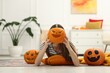 © New Africa - Happy Halloween. Woman hiding behind Jack-o'-lantern pumpkin at home