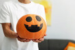 © New Africa - Halloween celebration. Man holding pumpkin with drawn spooky face indoors, closeup. Space for text