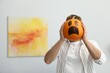 © New Africa - Halloween celebration. Man holding pumpkin with drawn spooky face at home, space for text