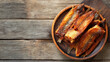 © Sabana - A wooden plate filled with smoked fish on a wooden surface in sunlight