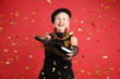 © New Africa - Happy senior woman with bottle of sparkling wine and flying confetti against red background