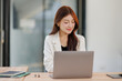 © David - Smiley young business asian woman holding business plan note and sitting at desk in modern coworking office.