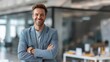 © Plaifah - Confident young man in business attire smiling in modern office environment with bright natural light creating a welcoming atmosphere for productivity