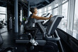 © Nomad_Soul - Senior woman riding an exercise bike in a bustling gym