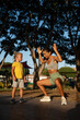 © sutulastock - Young athletic woman in a sports outfit doing a deep squat with raised arms in a sunny park, while her little son in casual clothes watches her seriously and attentively during an outdoor workout