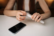 © dikushin - Cropped shot of woman opening white retail box containing new phone cable adapter, holding over clean white table with smartphone positioned nearby, showcasing excitement and anticipation.