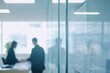 © imagepocket pro - A blurred office scene shows business professionals in discussion behind a glass wall filled with strategic plans and detailed project notes.