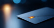 © perfectlab - A blue credit card with a chip is sitting on top of a dark surface, and it has an orange light shining through the chip