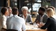 © irawan - Diverse group of professionals engaging in discussion around a conference table