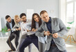 © Studio Romantic - Business team in formal attire playing tug of war with rope in office. Competitive colleagues having fun together and engaging in team building activity while strengthening their collaboration.