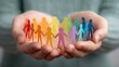 © victor - Hands holding colorful paper cutout people figures connected together. Teamwork, unity, diversity, and friendship concept. Paper dolls representing different cultures and cooperation.