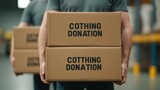 A person carries boxes labeled "Clothing Donation" in a storage area, highlighting the act of giving and community support.