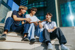 © Alexandr - Three teenage boys chatting and smiling while sitting on outdoor stairs