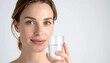© Athichai - Close-up of woman drinking clear water from glass, refreshing expression, bright white studio lighting