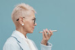 © TrueFrame Collective - Middle-aged woman using voice assistant on her smartphone side view horizontal shot