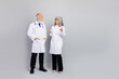 © deagreez - Two experienced doctors in white coats discuss patient care and medical topics in a modern clinic against a soft grey backdrop
