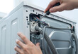 © Mahmuda - Professional washing machine repair service troubleshooting electric wiring | Hands using screwdriver to fix broken household laundry appliance | Appliance technician maintenance