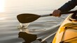 © Amena - Person paddling kayak on calm water at sunset