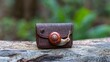 © Gefo - Creative snail figurine on a brown textured wallet outdoors, surrounded by greenery and natural light