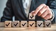 ©  Arif photos - Hand selecting a wooden cube with a checkmark from a row of cubes checklist selection