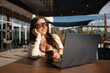 © WellStock - Woman using smartphone and laptop outdoors