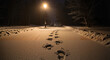 © Arties - Lone streetlamp shining over single set of footprints in deep snow