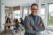 © Miljan Živković - Smiling business leader with arms crossed in modern office
