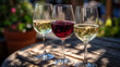 © Maksym - Trio of wine glasses arranged on a rustic wooden table outdoors, each holding a different hue of wine, golden daylight reflections enhancing the vibrant colors