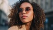 © Johannes - Young mixed race African American woman wearing stylish sunglasses standing on city street looking away, portrait. Gen z Afro American ethnic lady in trendy glasses closeup face headshot., no logos,