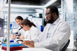 © DC Studio - Laboratory molecular biologist using computer software to process DNA patient data for clinical research. African american man uses PC program to do lab genetic analysis diagnostics