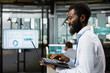 © DC Studio - Corporate professional focused on business analytics and financial planning, working on laptop. Black male employee organizing online files and preparing key project presentation at office.