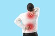 © Pixel-Shot - Young businessman suffering from back pain on blue background
