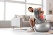 © Pixel-Shot - Sporty young man suffering from back pain while training with fitball at home