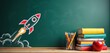 © Viktor - Chalk drawing of a rocket launching on a green chalkboard next to a stack of books and colored pencils. An apple sits on top of the book pile. Represents education and new beginnings.