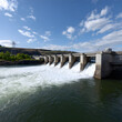 © MonkeyZ - Scenic Hydroelectric Dam with Flowing Water in a Sunny Landscape Under a Blue Sky