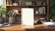 © Viktor - Blank paperback book on wooden desk. Design supplies like markers, sketchpads, stapler nearby. Book cover mockup for advertising, education literature use. Office workspace with plants, bookshelf in