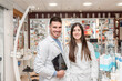 © Renata Hamuda - Two young diverse pharmacists smiling at camera in a pharmacy holding a digital tablet