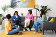 © Studio Marmellata - Four diverse young women are enjoying a friendly conversation in a modern living room. They are smiling and interacting, sharing a relaxed social moment together.