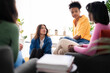 © Studio Marmellata - A diverse group of young women engages in a thoughtful discussion indoors. They are sharing perspectives and actively listening to each other in a comfortable, collaborative environment.
