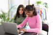 © Studio Marmellata - Two diverse young women work together on a laptop in a bright, modern setting. One types on the keyboard while the other watches intently, engaged in their shared project.