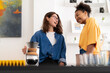 © Studio Marmellata - Two cheerful young women, one with glasses, are enjoying a conversation in a bright, modern home. One holds a pour-over coffee maker, sharing a happy moment.