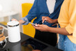 © Studio Marmellata - Two individuals are in a bright, modern kitchen. One person handles a sleek white electric kettle, while the other scrolls on a smartphone. They are making coffee.