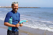 © Inspiraciones - Happy middle-aged man before diving into the sea wearing a wetsuit, goggles, and snorkel.