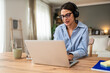 © Srdjan - Happy freelance businesswoman in headphones leading remote coaching call from home workspace speaking to laptop during virtual webinar client consultation mentoring strategy planning home office
