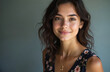 © miss irine - Young woman with dark wavy hair and brown eyes smiles gently. She wears a floral top and a delicate necklace. Her natural beauty shines in soft indoor lighting with copy space.