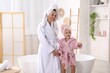 © New Africa - Mother and daughter wearing bathrobes with their hair wrapped in towels at bathroom