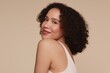 © Eve - Portrait of smiling young woman with curly hair and glowing skin posing on beige background. Natural beauty, skincare, confidence, self-love and body positivity concept for modern lifestyle.