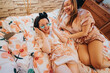© qunica.com - Two women sharing a joyful moment on a floral bed during a skincare routine, enhancing friendship and relaxation.